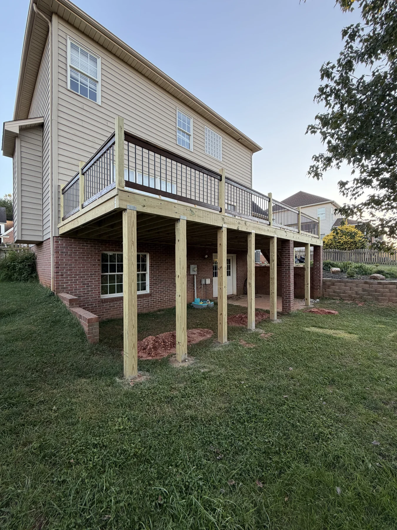 An elevated wood deck with perimeter railings and space outside the home. The photographs document the timber surface, the supporting structure and stages of the work.