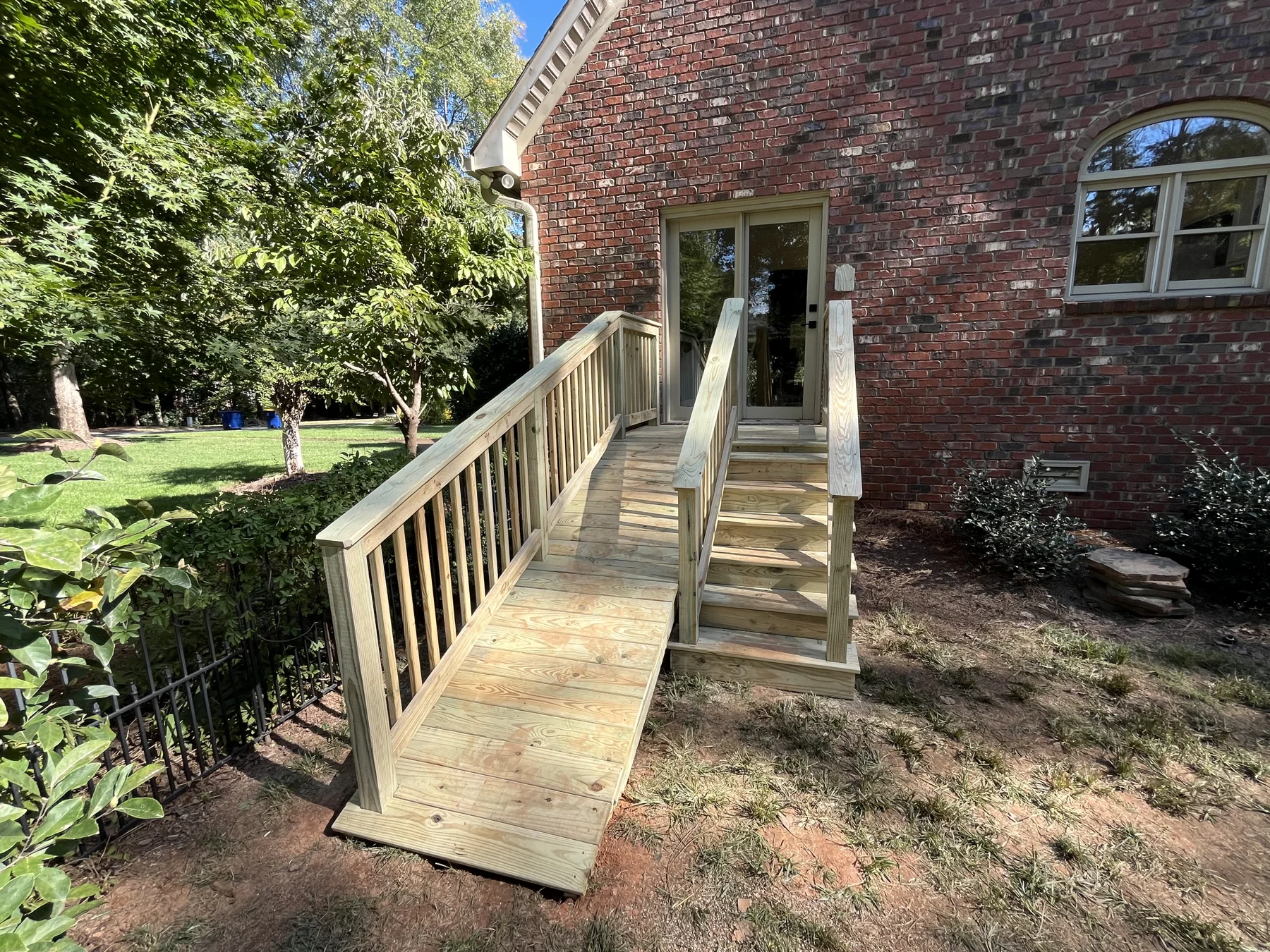 A timber staircase and landing create an outdoor route alongside a brick home. The supplied views show the stairs, rails and connection between the landing and surrounding yard.