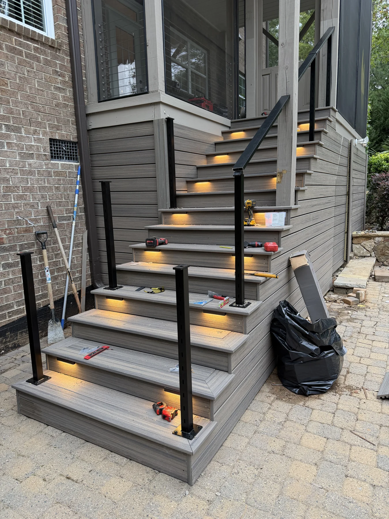 A backyard deck staircase with dark railings and illuminated treads. The gallery records the stair details, the connection to the elevated deck and the surrounding outdoor space.