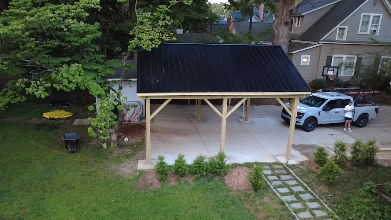 A freestanding timber carport with a dark roof provides shelter over the driveway. Finished and framing views show the posts, bracing and open structure alongside the home.