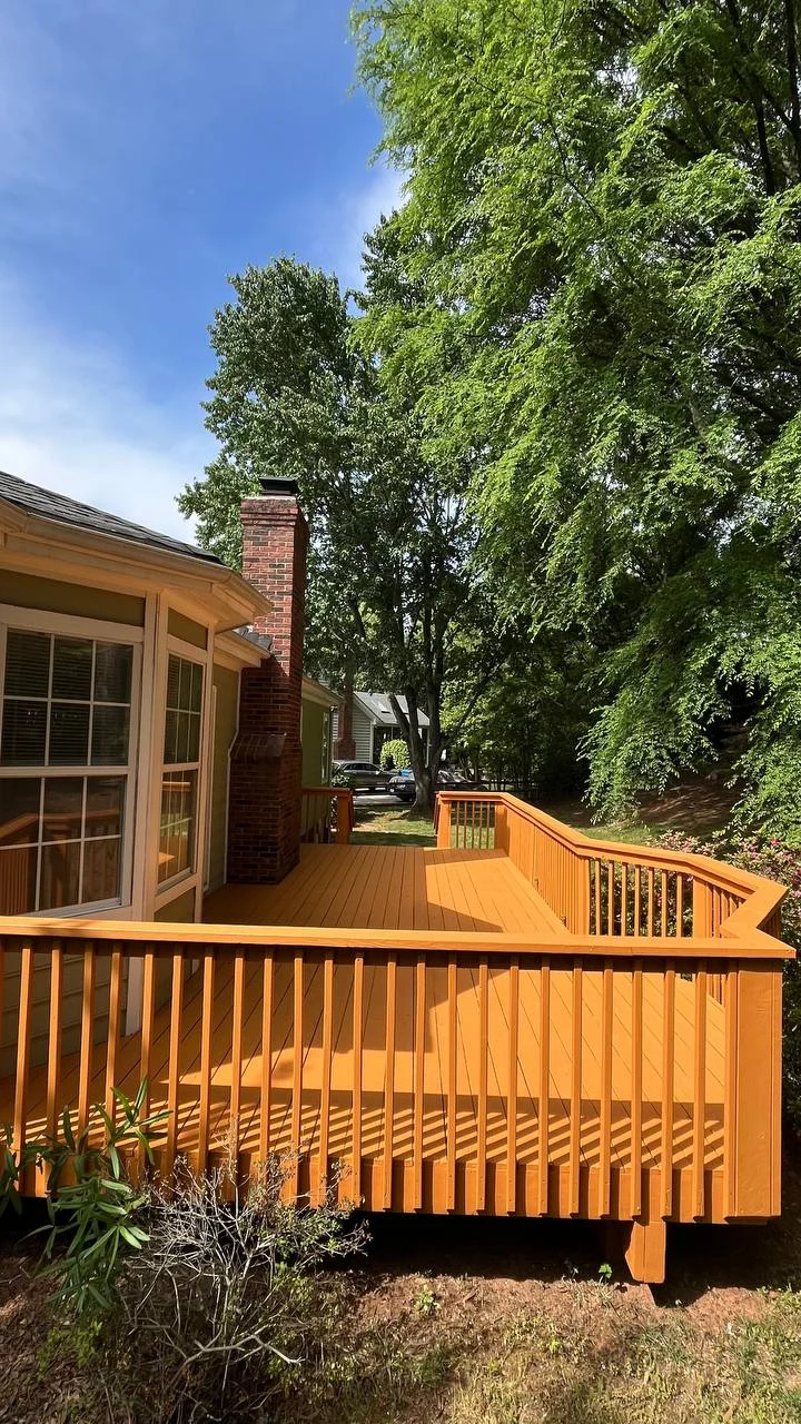 A wood deck with matching timber rails and broad steps extends the living space into the backyard. Warm-toned boards and a straightforward layout give the outdoor space a consistent finish.