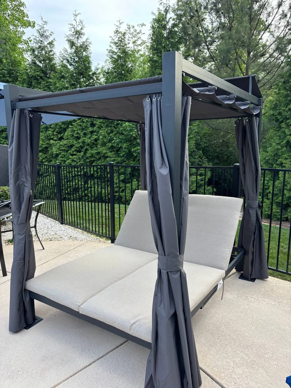 A modern pergola provides a defined seating area next to the home. The supplied photograph shows its clean frame, roof arrangement and screen elements around the patio.