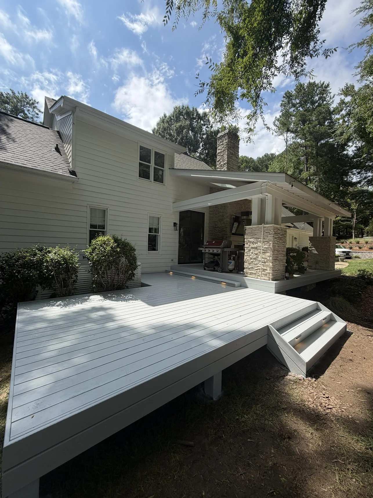 A custom wood deck complements the architecture of the home with broad transitions and a clean outdoor layout. A custom HVAC privacy screen adds a practical finishing detail.