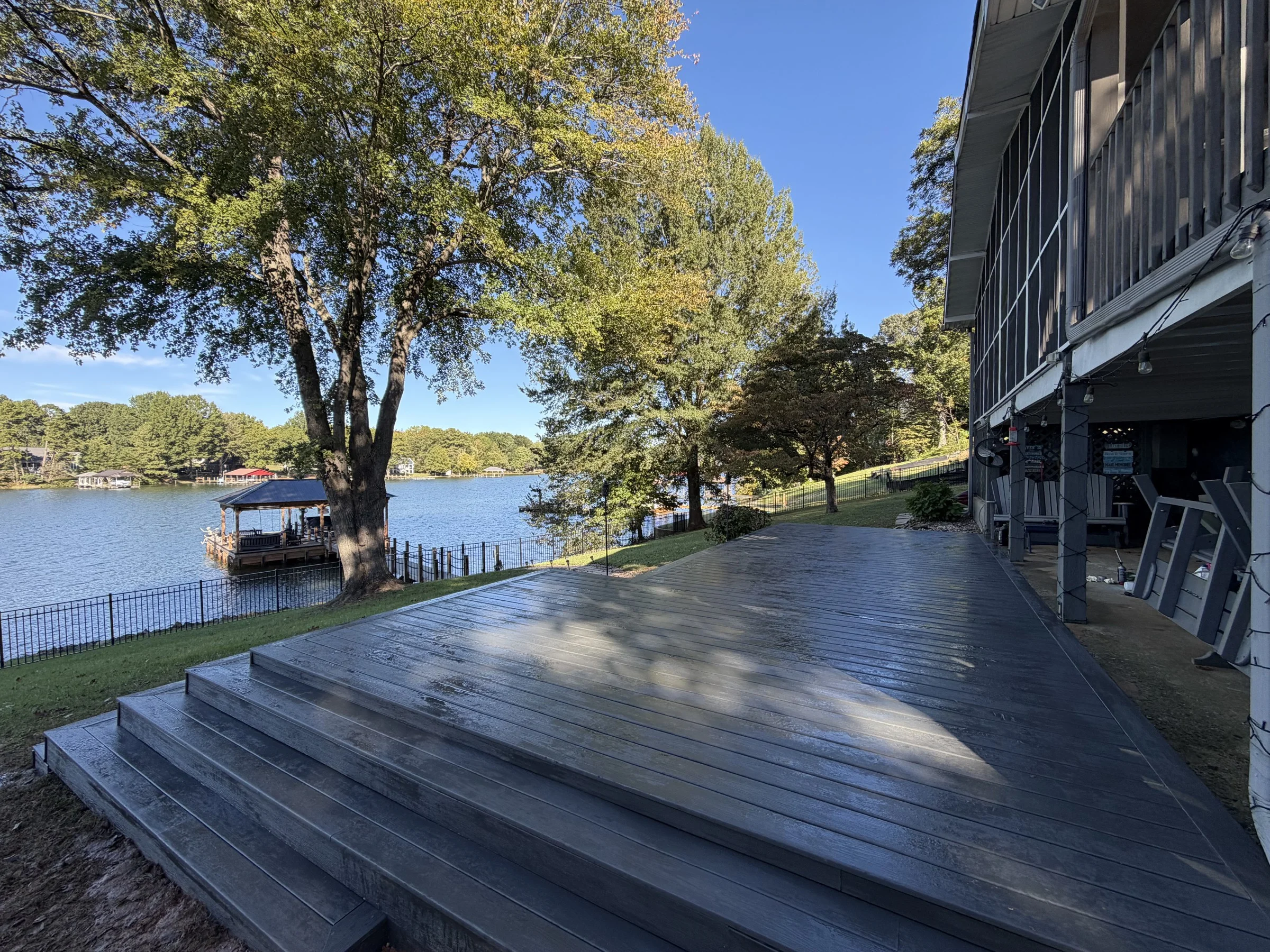 A custom 32 &times; 16 ft deck built from the ground up on a sloped Lake Norman property, creating 512 square feet of outdoor living space. Custom structural framing keeps the deck level as the ground falls from less than one foot to several feet below the surface. Precision-installed decking, picture-frame borders and carefully aligned boards give the space a clean, cohesive finish. Wraparound stairs use varying step configurations to follow the natural terrain, providing access to the yard from multiple directions while preserving the lake views. Thoughtful design and detailed finish carpentry bring the deck, stairs and surrounding landscape together.